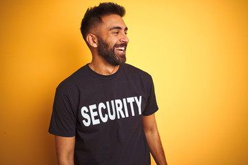Arab indian hispanic safeguard man wearing security uniform over isolated yellow background looking...