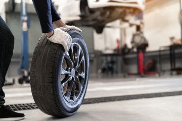 Mechanic man change a wheel tyre and service maintenance the suspension of a vehicle , Safety inspection test engine before customer drive a car on a long journey, transportation service