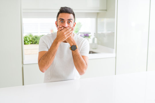 Handsome hispanic man casual white t-shirt at home shocked covering mouth with hands for mistake. Secret concept.