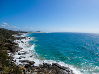 Bright sunny summer beach day with vivid blue ocean in the background and cliffs in the foreground at Point Arkwright, Sunshine Coast, Queensland, Australia