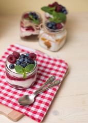 Raspberry cakes in glass jar with fresh fruit and cream cheese on a red napkin.