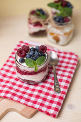 Raspberry cakes in glass jar with fresh fruit and cream cheese on a red napkin.