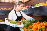 Salesgirl arranging goods in greengrocery
