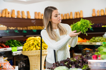Girl choosing greens in supermarket