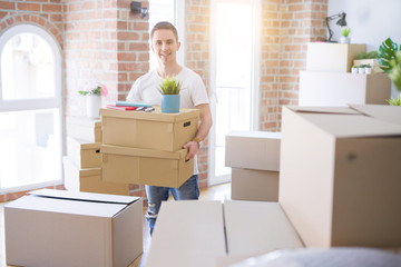 Fototapeta premium Young handsome man moving cardboard boxes at new home