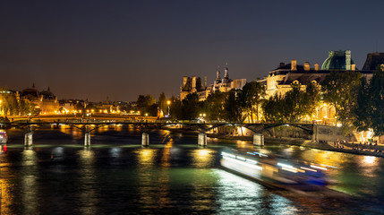 Fototapeta na wymiar Nightfall over Seine river and illuminated Pont des arts with palais royal and musee d'orsay in background - Paris, France