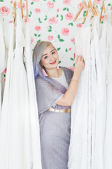 Fototapeta premium Bride is poses among white wedding dresses..