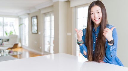 Fototapeta na wymiar Young beautiful asian woman with long hair wearing denim jacket success sign doing positive gesture with hand, thumbs up smiling and happy. Cheerful expression and winner gesture.