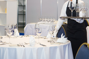 Waitress dressed in the uniform serving a set of wine glasses