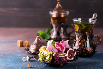 Traditional turkish sweets with tea mint in a traditional glass on a concrete background