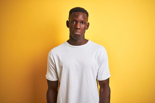 Young african american man wearing white t-shirt standing over isolated yellow background depressed and worry for distress, crying angry and afraid. Sad expression.