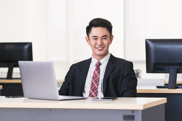 Asian businessman smiling and sittting in office,.
