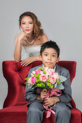 Bride sitting with son, he holding a bouquet..