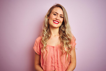 Young beautiful woman wearing t-shirt standing over pink isolated background with hands together and crossed fingers smiling relaxed and cheerful. Success and optimistic