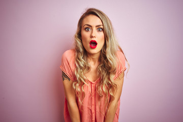 Young beautiful woman wearing t-shirt standing over pink isolated background afraid and shocked with surprise and amazed expression, fear and excited face.