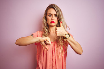 Young beautiful woman wearing t-shirt standing over pink isolated background Doing thumbs up and down, disagreement and agreement expression. Crazy conflict