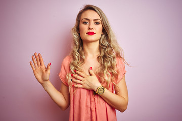 Young beautiful woman wearing t-shirt standing over pink isolated background Swearing with hand on chest and open palm, making a loyalty promise oath