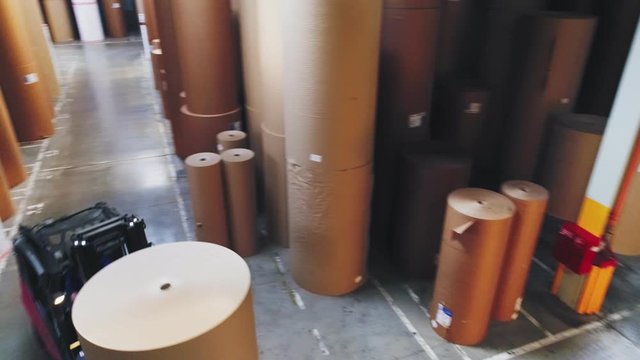 forklift loader carries paper roll along pass in storehouse