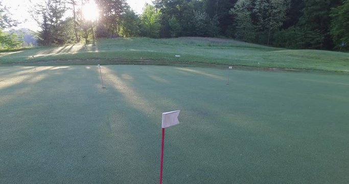 Camera down walk thru golf putt course, early in the morning.
