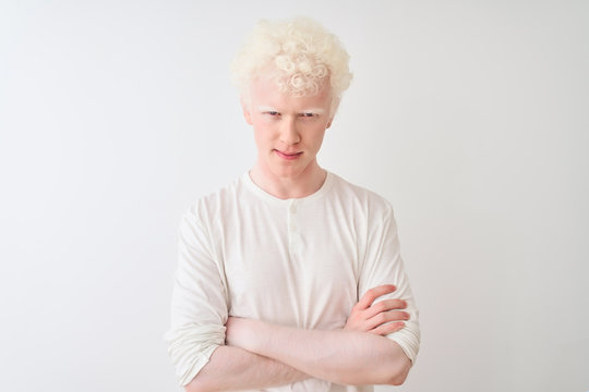 Young albino blond man wearing casual t-shirt standing over isolated white background skeptic and nervous, disapproving expression on face with crossed arms. Negative person.