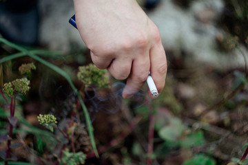 Smoking cigarette in a man's hands on a background of green grass