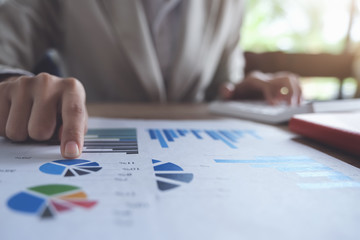 Business accounting concept, Business man pointing graph chart and using calculator to calculating budget and loan paper in office.