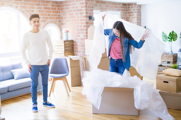 Young asian couple having fun  playing with bubble wrap smiling happy moving to a new house