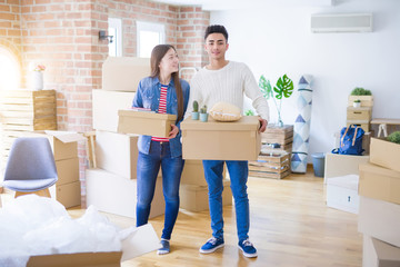 Fototapeta na wymiar Beautiful young asian couple looking happy holding cardboard boxes, smiling excited moving to a new home
