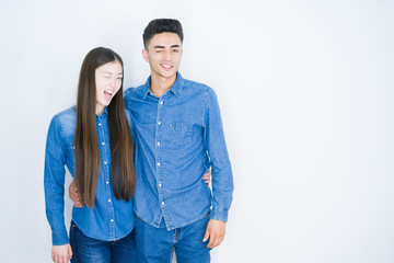 Beautiful young asian couple over white isolated background winking looking at the camera with sexy...