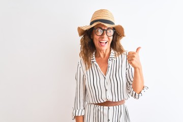 Obraz na płótnie Canvas Middle age businesswoman wearing striped dress glasses hat over isolated white background pointing and showing with thumb up to the side with happy face smiling