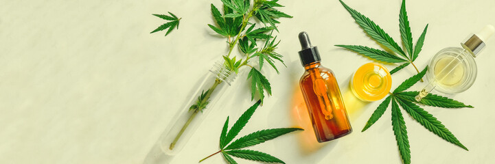 Various glass bottles with CBD oil, THC tincture and hemp leaves on a marble background. Flat lay,...