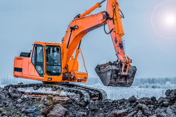 Excavator is loading excavation to the truck. Excavators hydraulic are heavy construction equipment consisting of a boom, dipper or stick , bucket and cab on a rotating platform.