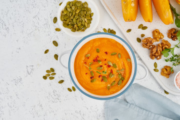 Pumpkin cream soup with seeds, top view light white background copy space
