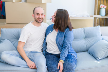 Young couple in love relaxing and hugging sitting on the sofa at new home, smiling very happy for moving to a new apartment