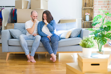 Fototapeta na wymiar Young couple sitting on the sofa arround cardboard boxes moving to a new house feeling unwell and coughing as symptom for cold or bronchitis. Healthcare concept.