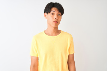 Chinese man wearing yellow casual t-shirt standing over isolated white background Relaxed with serious expression on face. Simple and natural looking at the camera.