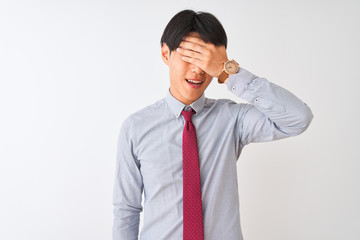 Chinese businessman wearing elegant tie standing over isolated white background smiling and laughing with hand on face covering eyes for surprise. Blind concept.