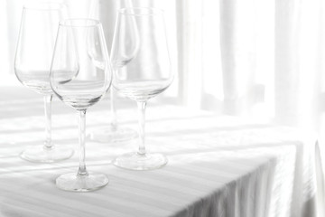 Several empty wine glasses in white grey shades on the white tablecloth
