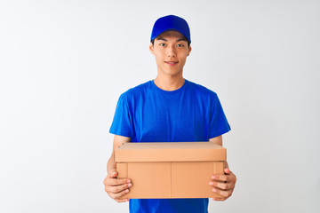 Chinese deliveryman wearing cap holding box standing over isolated white background with a happy face standing and smiling with a confident smile showing teeth