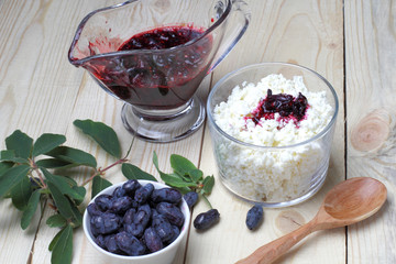 Fresh honeysuckle berries and jam, natural cottage cheese on a wooden table, breakfast concept in...