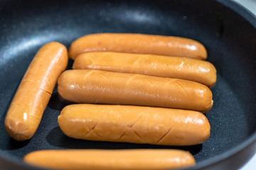 Close Up view of sausages fried in a pan, Sensitive Focus, Macro photo of food being cooked.