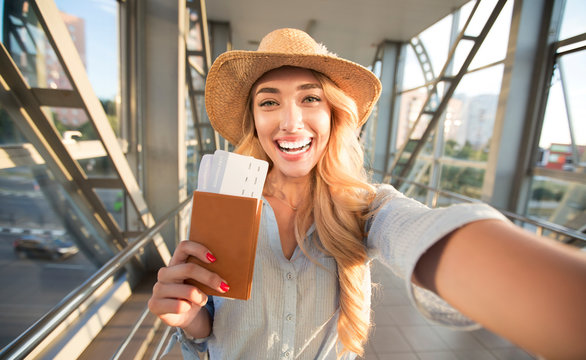 Happy woman taking selfie in airport, waiting for boarding