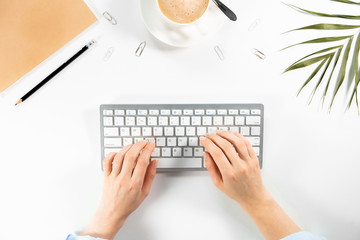 Woman's hands are typing on a computer keyboard, office flatlay workspace. Desktop.