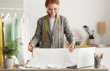 Seamstress choosing fabric and touching it in studio