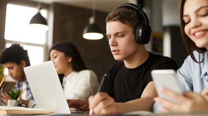 Students in library. Guy listening music in headphones