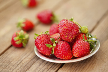 Strawberries on a plate on wooden background