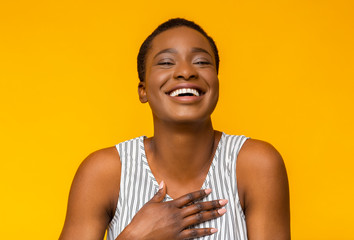 Funny afro girl laughing at camera on yellow background