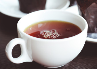 White cup with black tea on the table, dessert