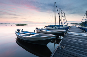 yachts by pier on big lake at dawn