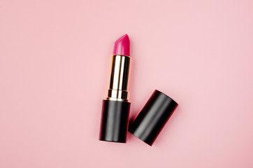 Pink lipstick tube, lip gloss top view. Beauty industry concept. Glamorous makeup accessory close up on pastel pink background. Women fashion product, style. Cosmetology, female elegance attribute